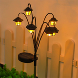 Retro hexagonal solar stake light glowing warm white on a garden path