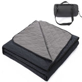 Grasmere double layer fleece picnic blanket in black folded beside its zippered shoulder carry bag on grass
