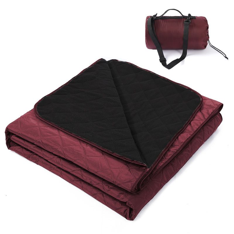 Grasmere double layer fleece picnic blanket in wine red folded beside its zippered shoulder carry bag on grass