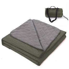 Grasmere double layer fleece picnic blanket in dark green folded beside its zippered shoulder carry bag on grass